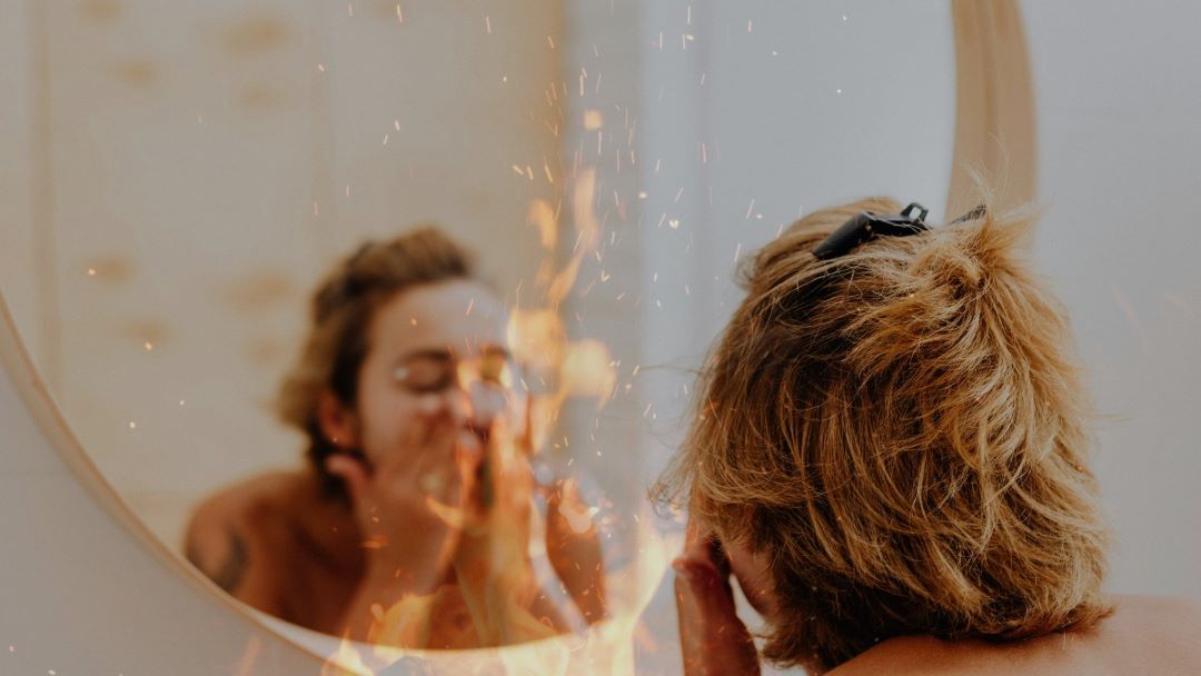 Brennende Haut im Gesicht: Frau bei der Gesichtsreinigung vor Spiegel, stilisierte Flamme, die das Brennen darstellt